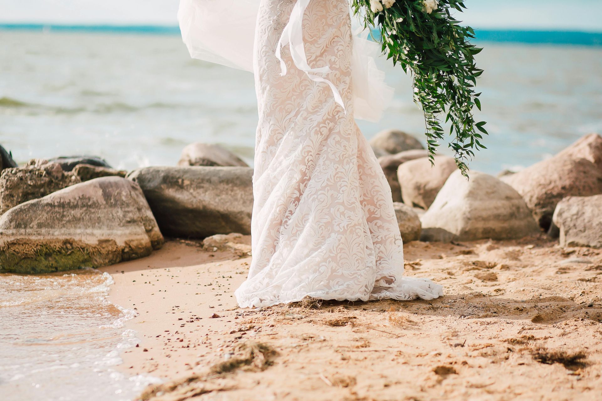 Bride with bouquet walking along the shore on rocks and sand