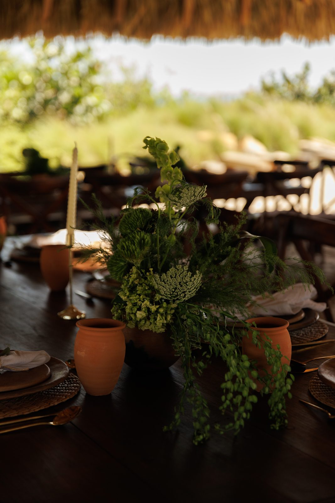 Lush green centerpiece with candle on rustic wedding table
