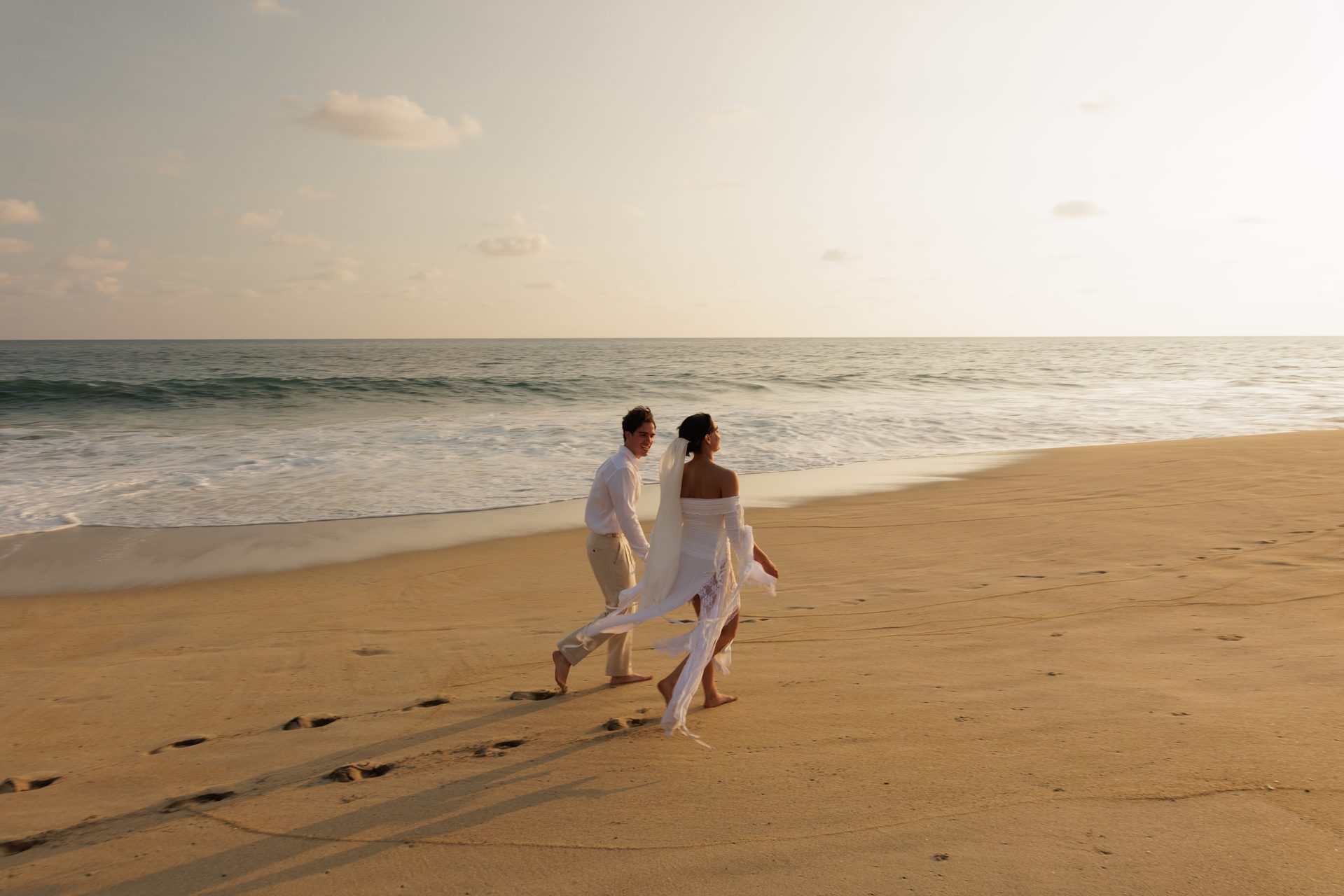Couple walking along the ocean shore at sunset